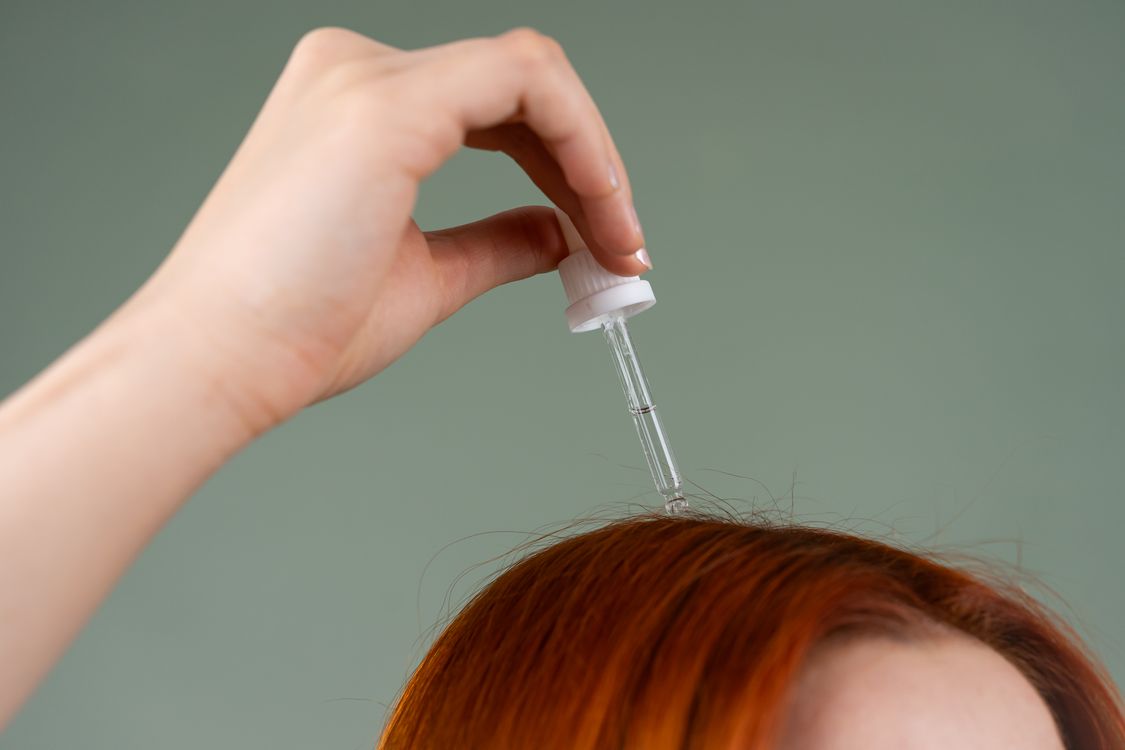Aplicação de sérum com conta-gotas no cabelo, contexto de tratamento para cabelo seco e danificado