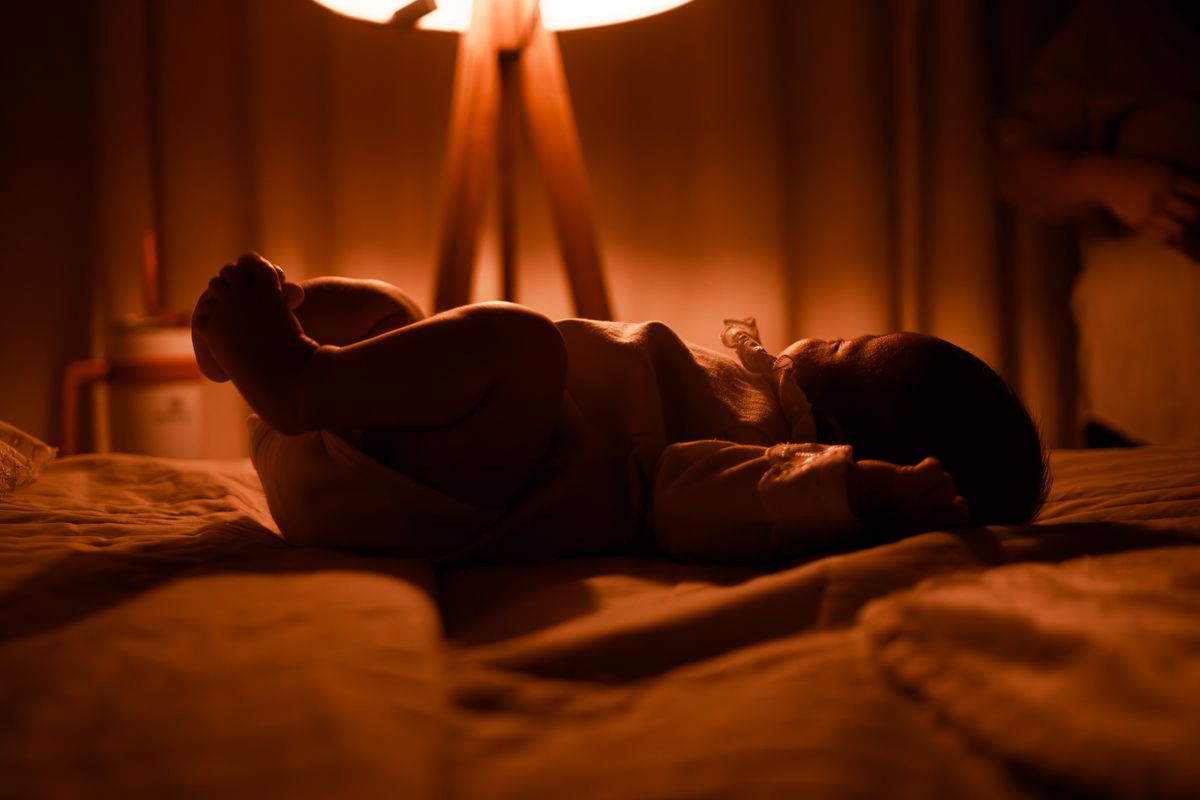 Bebê sereno dormindo sob a luz quente de um abajur - aquecedor de ambiente no quarto infantil