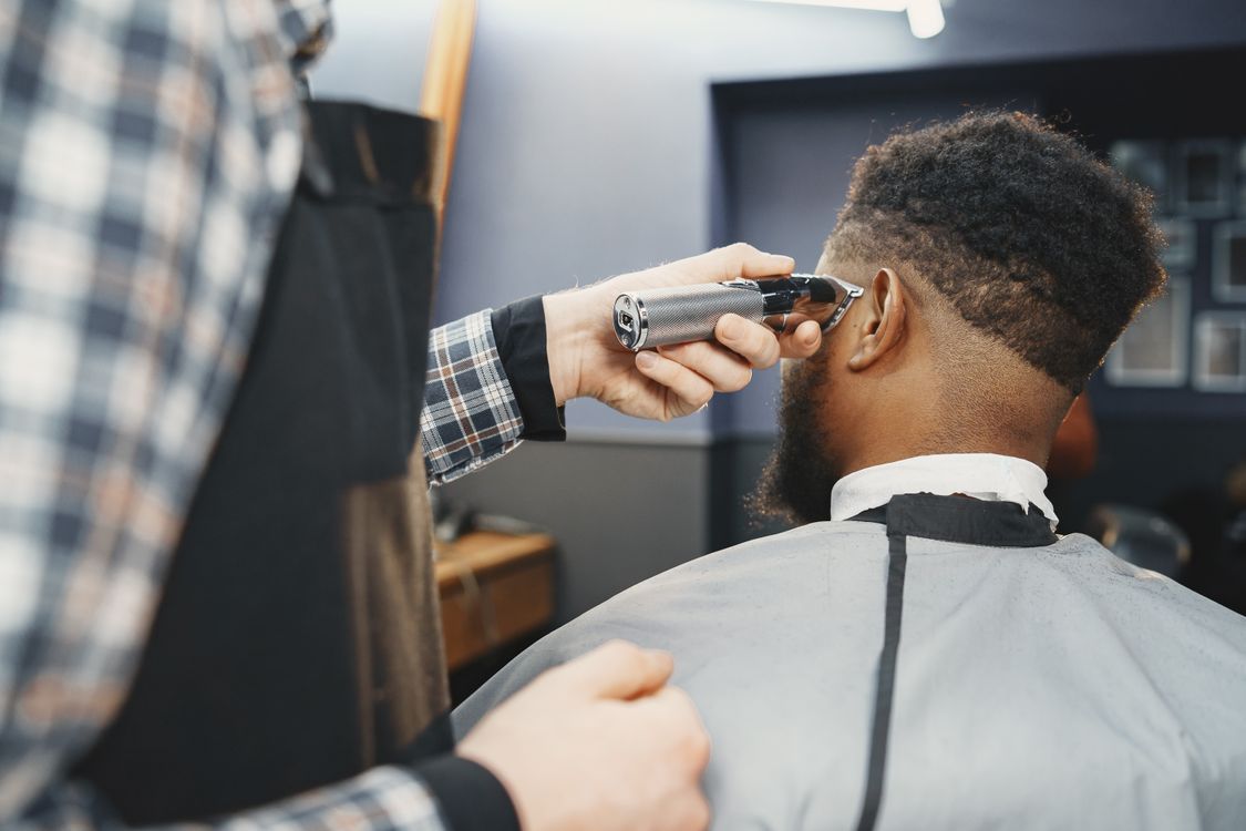 Barbeiro realizando corte com degradê usando máquina, contexto de máquina de cortar cabelo Kemei
