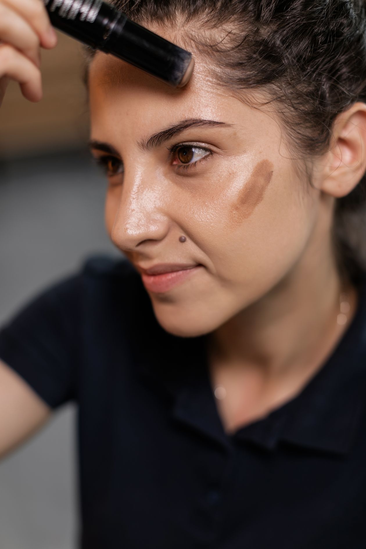 Mulher aplicando BB cream com protetor solar no rosto, contexto de maquiagem e proteção