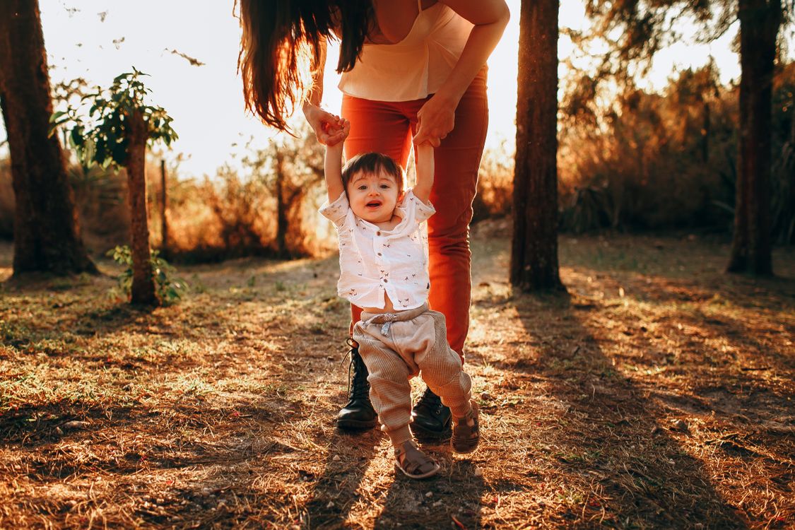 Mãe ajudando bebê a andar no parque, contexto de andador para bebê de 9 meses
