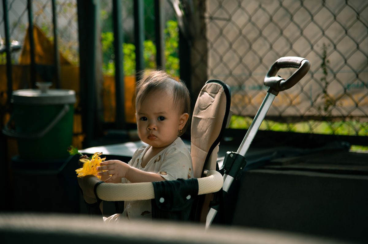 Bebê passeando em carrinho guarda-chuva ao ar livre, contexto de uso do carrinho de passeio leve