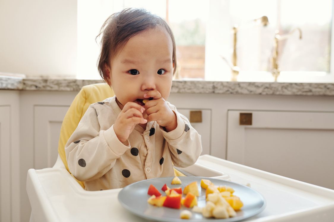 Bebê lanchando na cadeira de alimentação, contexto de biscoito de polvilho seguro para bebê