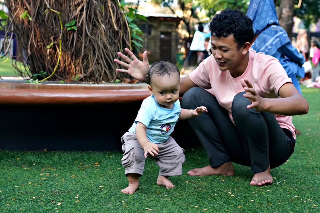 Pai apoiando os primeiros passos do bebê, contexto de escolha de andador para bebê de 9 meses