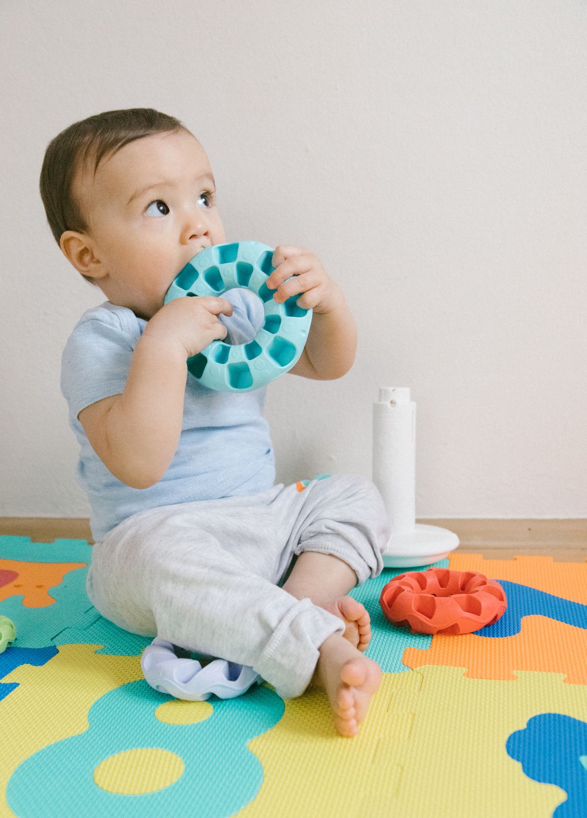 Bebê brincando com brinquedos sobre tatame de quebra-cabeça em casa, contexto de tatame infantil