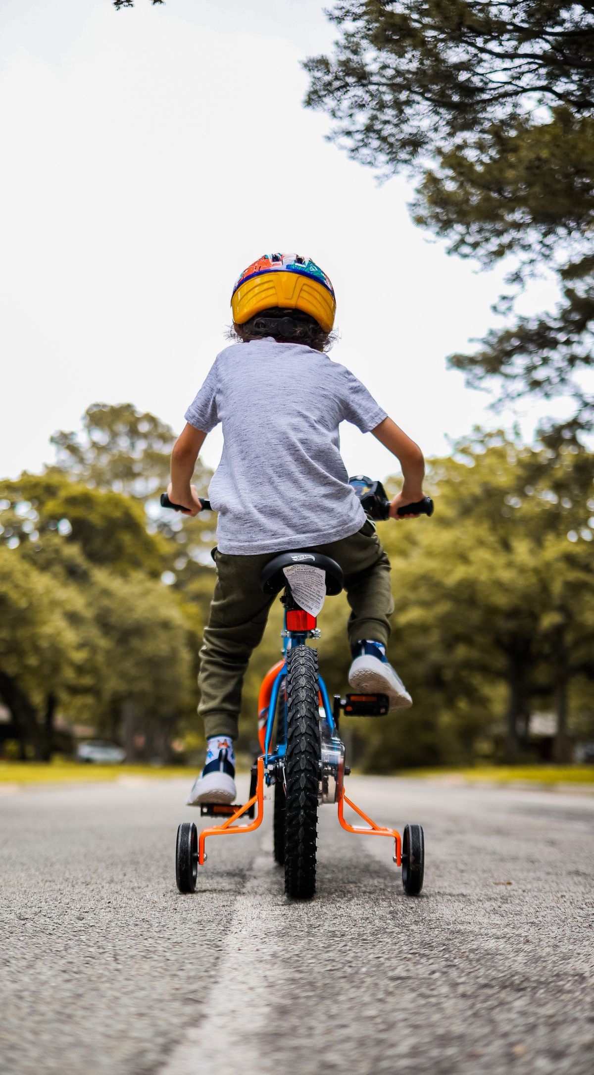 Menino andando de bicicleta em parque ensolarado - contexto de uso da bicicleta infantil