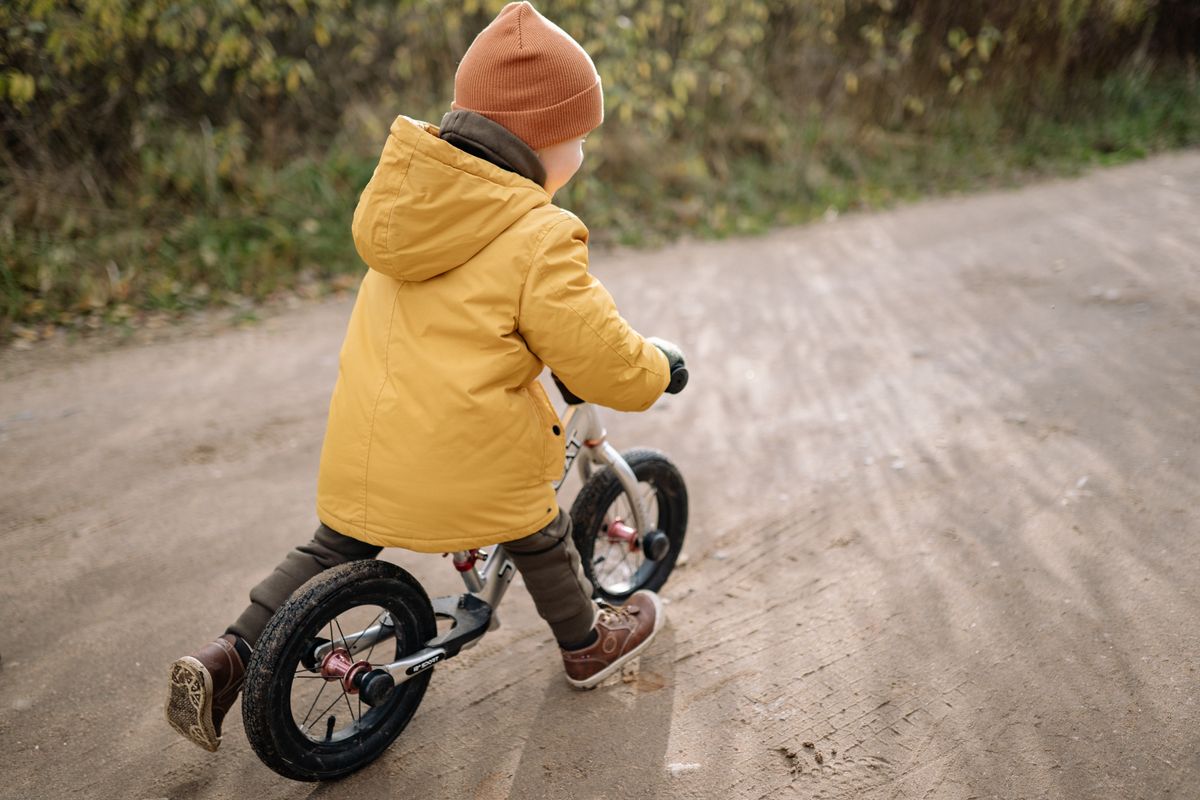 Crian�a brincando com bicicleta de brinquedo - contexto infantil da bicicleta
