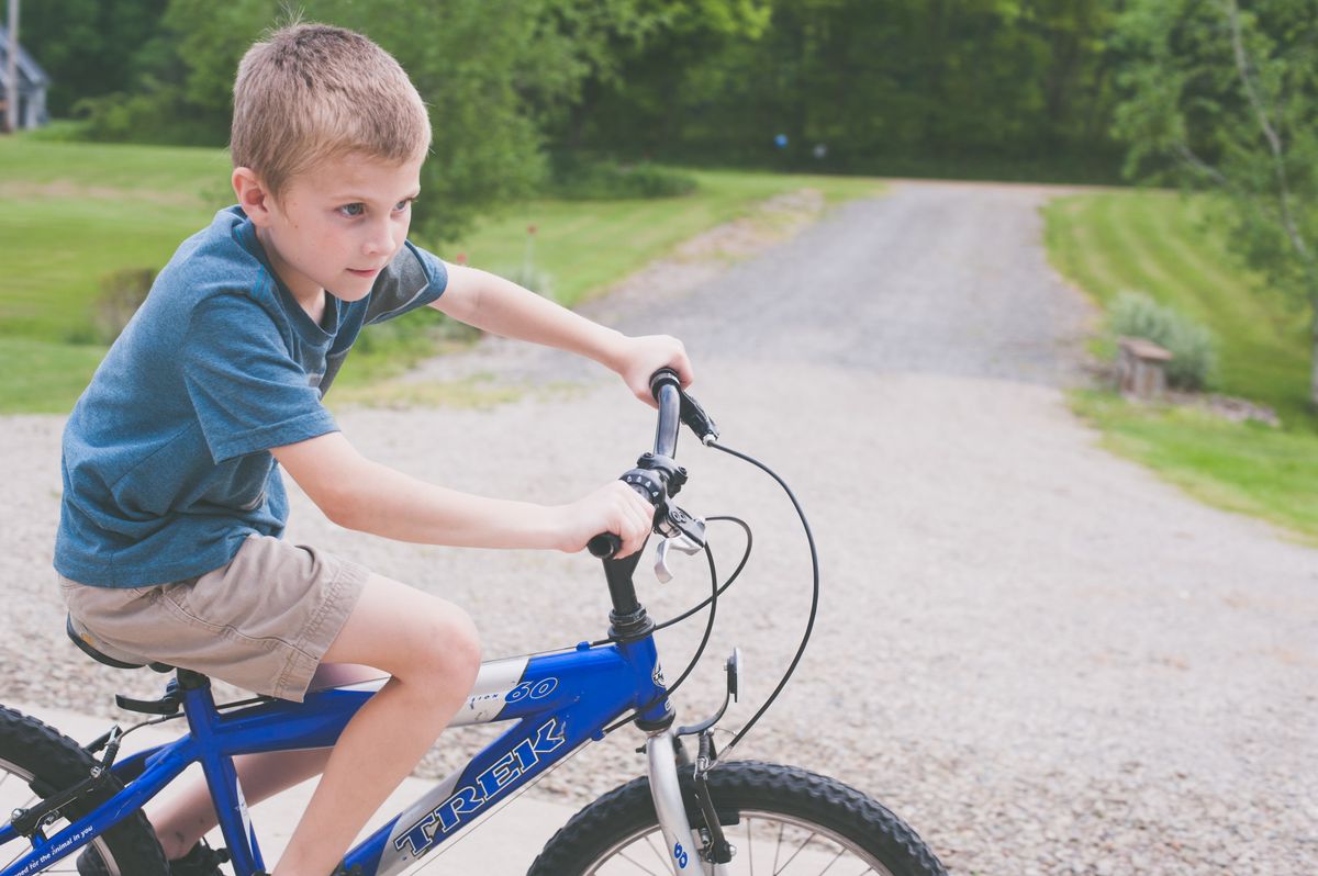 Criança andando de bicicleta infantil em trilha na natureza