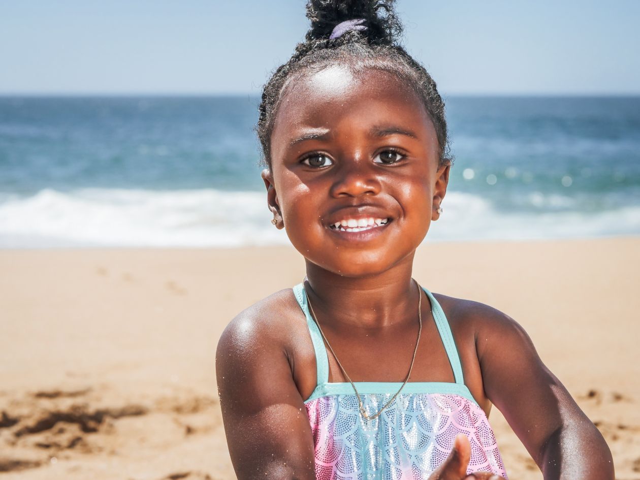 Menina de biquíni brincando na praia, contexto de melhor marca de biquíni infantil
