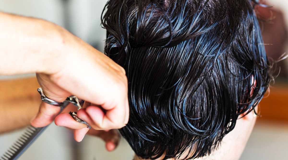 Cabeleireiro cortando cabelo com tesoura profissional em salão, contexto de escolha de tesoura de cabelo