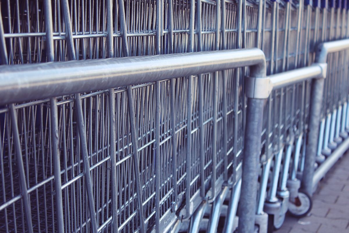 Carrinhos de compras de metal em primeiro plano, detalhe das rodas e estrutura do carrinho de feira