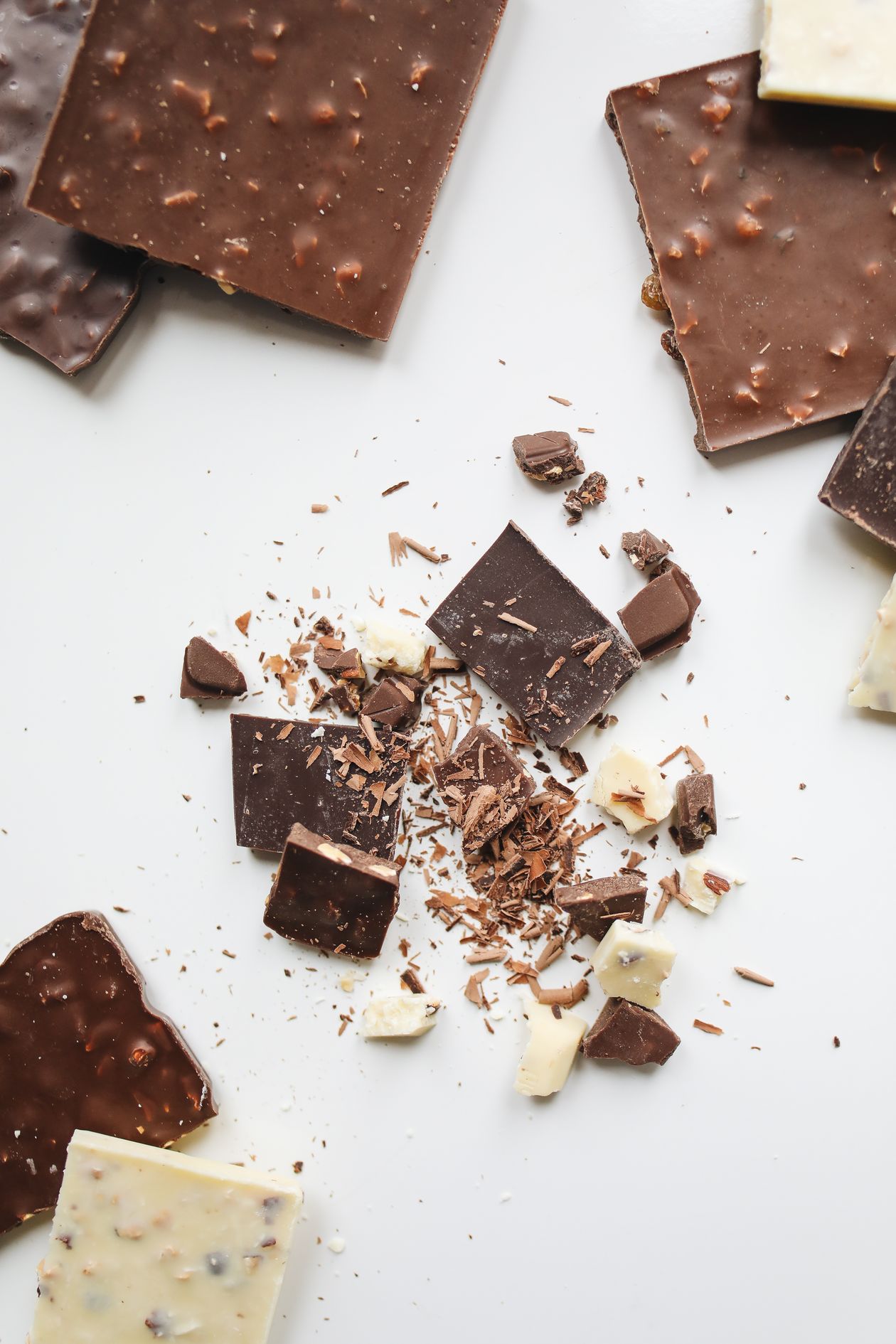 Chocolate fracionado em gotas e pedaços sobre bancada de confeitaria, contexto de melhor chocolate ao leite fracionado