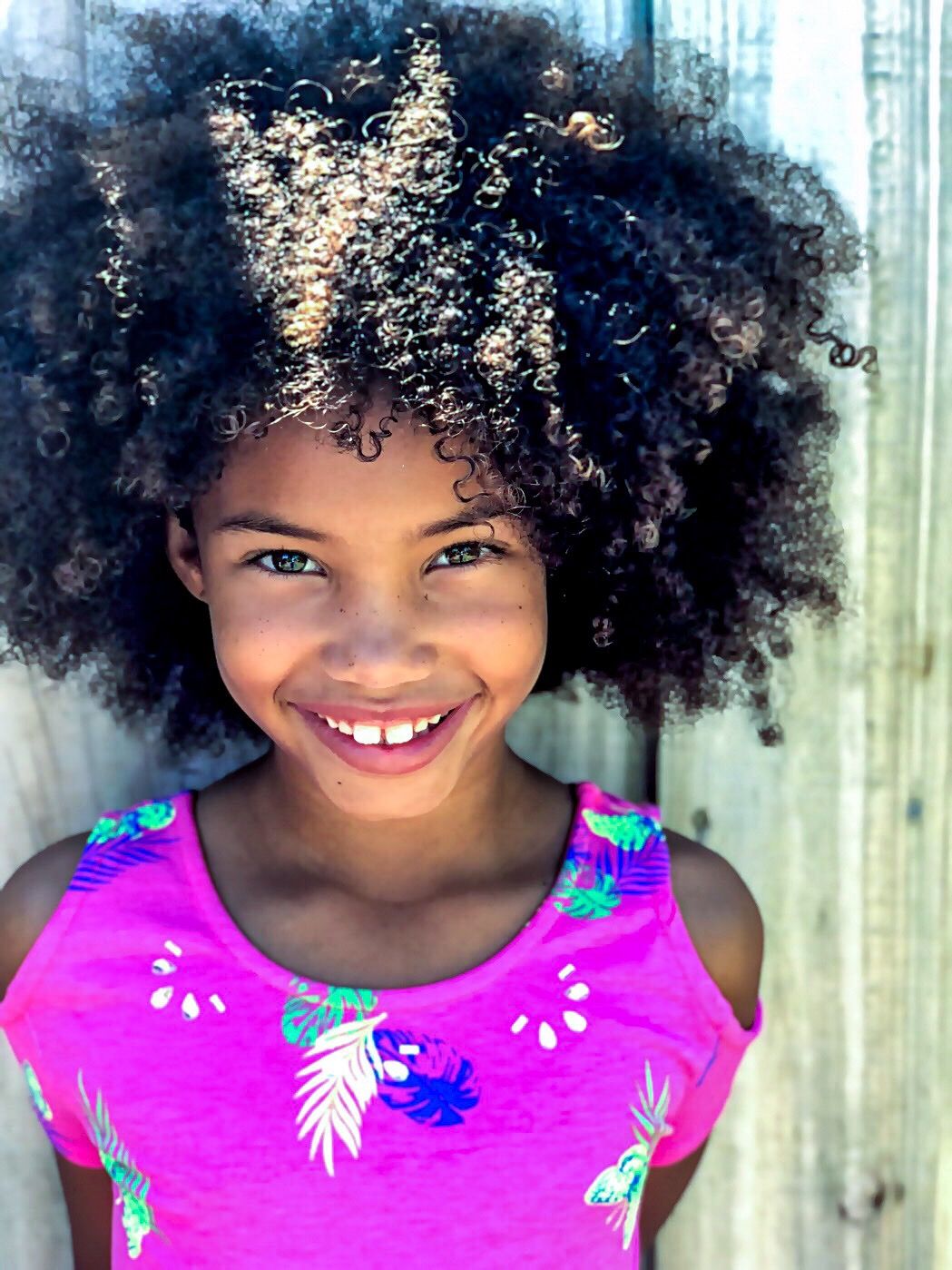 Criança sorrindo com cabelo cacheado solto, contexto de melhor condicionador infantil para cabelos cacheados