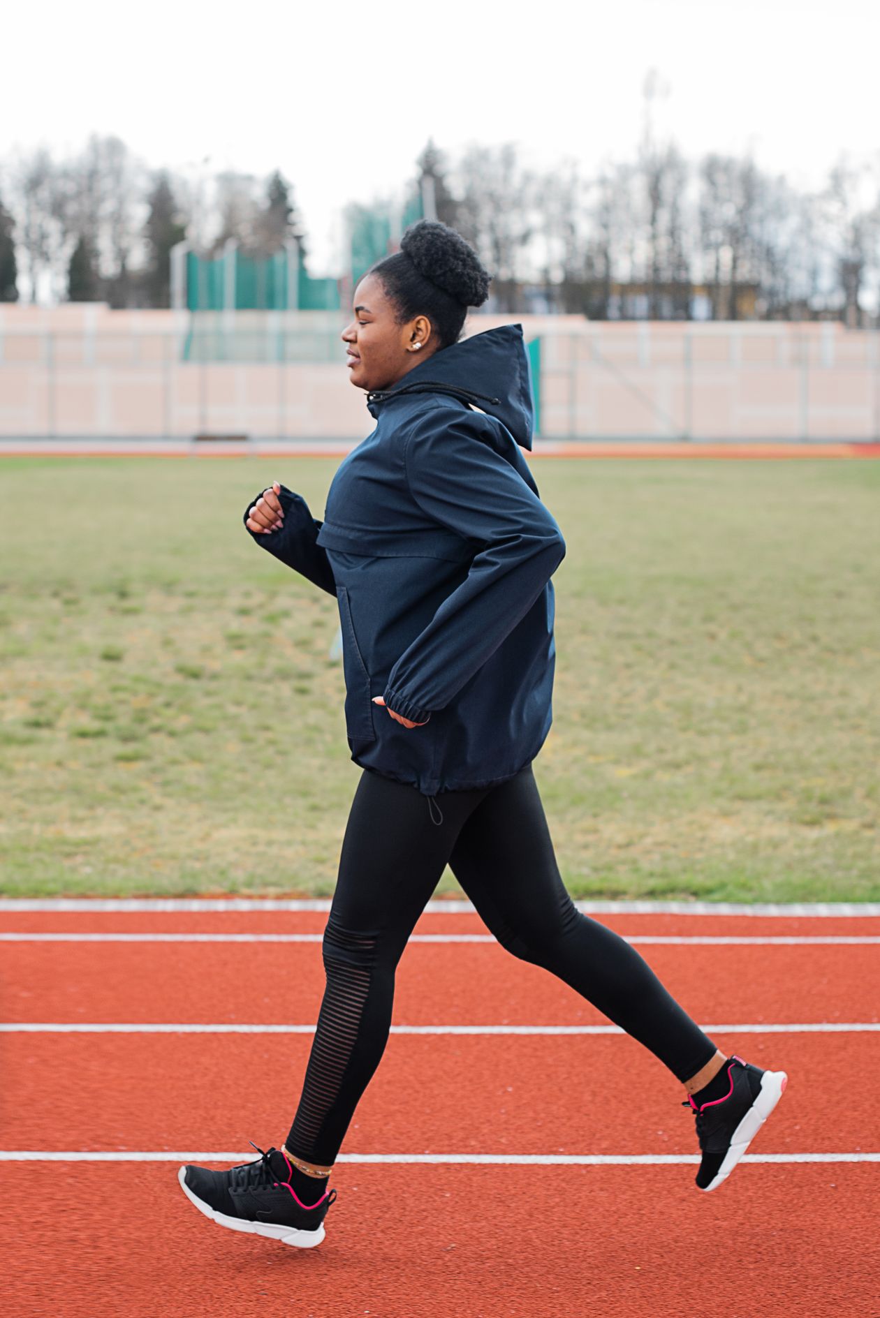 Mulher correndo em pista de atletismo com tênis Mizuno feminino, contexto de tênis mizuno para corrida feminino