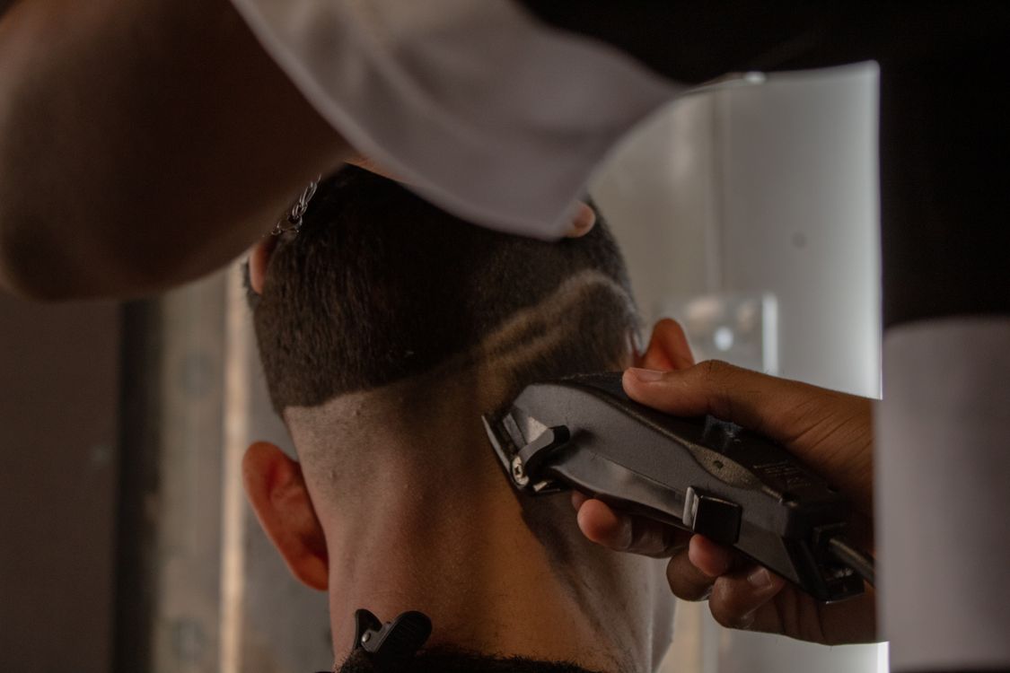 Corte de cabelo com máquina em barbearia profissional, contexto de máquina Wahl em uso