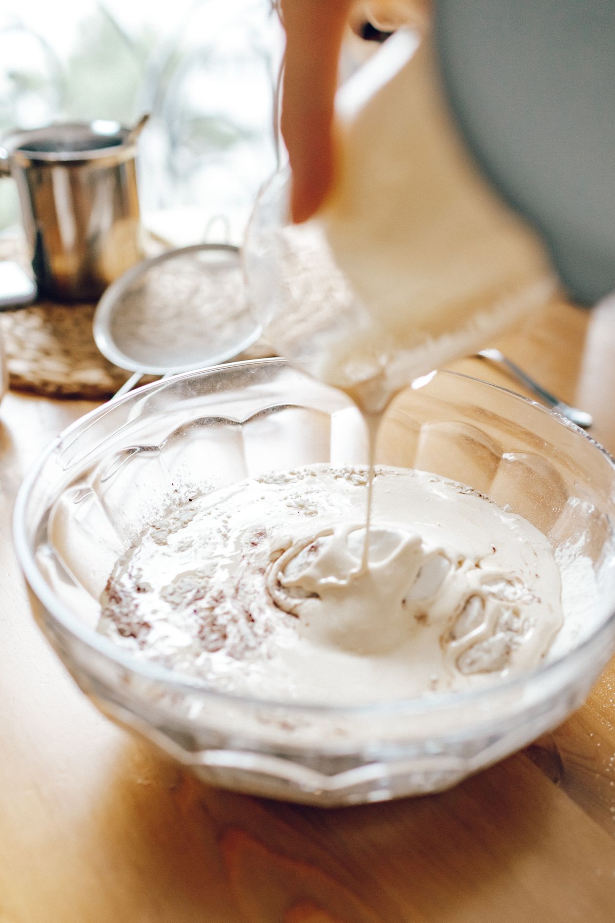 Creme de leite sendo vertido em uma tigela de vidro durante o preparo de uma receita
