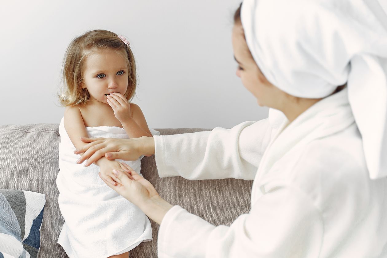 Mãe aplicando hidratante na pele do bebê durante a rotina de cuidados