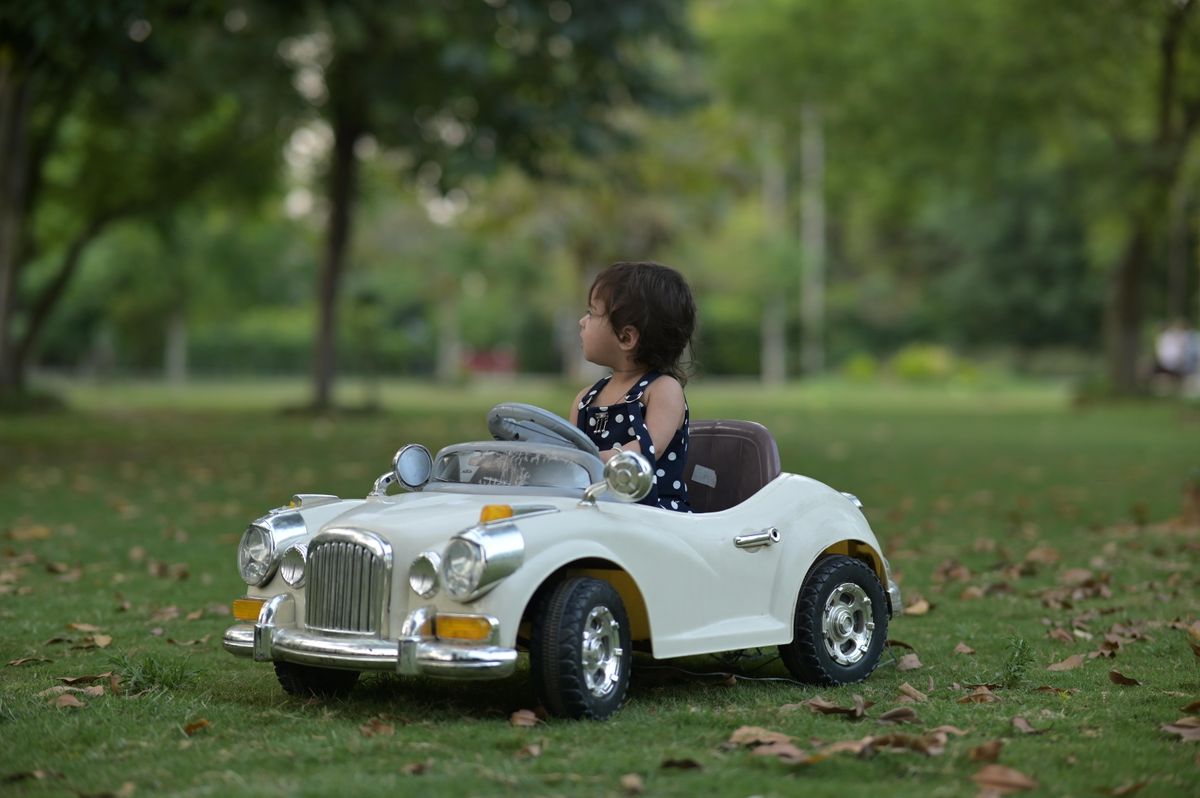 Criança com carrinho elétrico no parque, contexto de uso do carrinho elétrico infantil ao ar livre