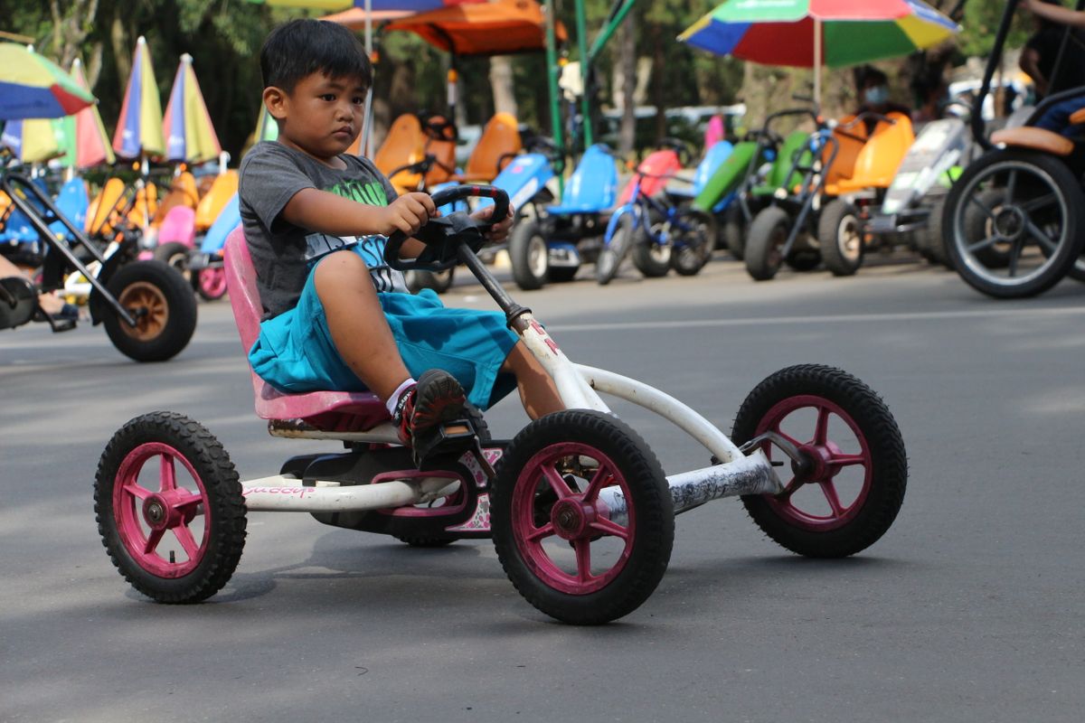 Criança pedalando kart em parque, contexto de uso do carrinho de pedal ao ar livre