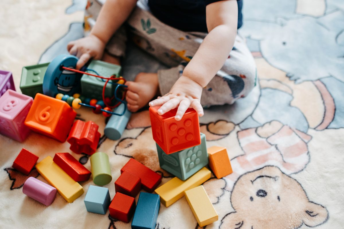Criança pequena brincando com blocos sobre tatame estampado, contexto de tatame para bebê