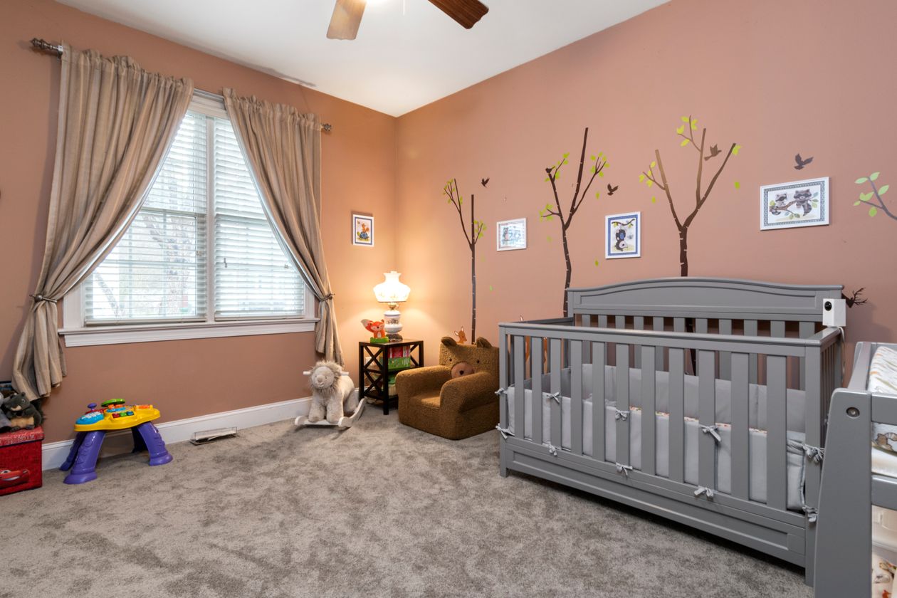Quarto infantil com berço, poltrona e decoração, contexto de melhor despertador infantil