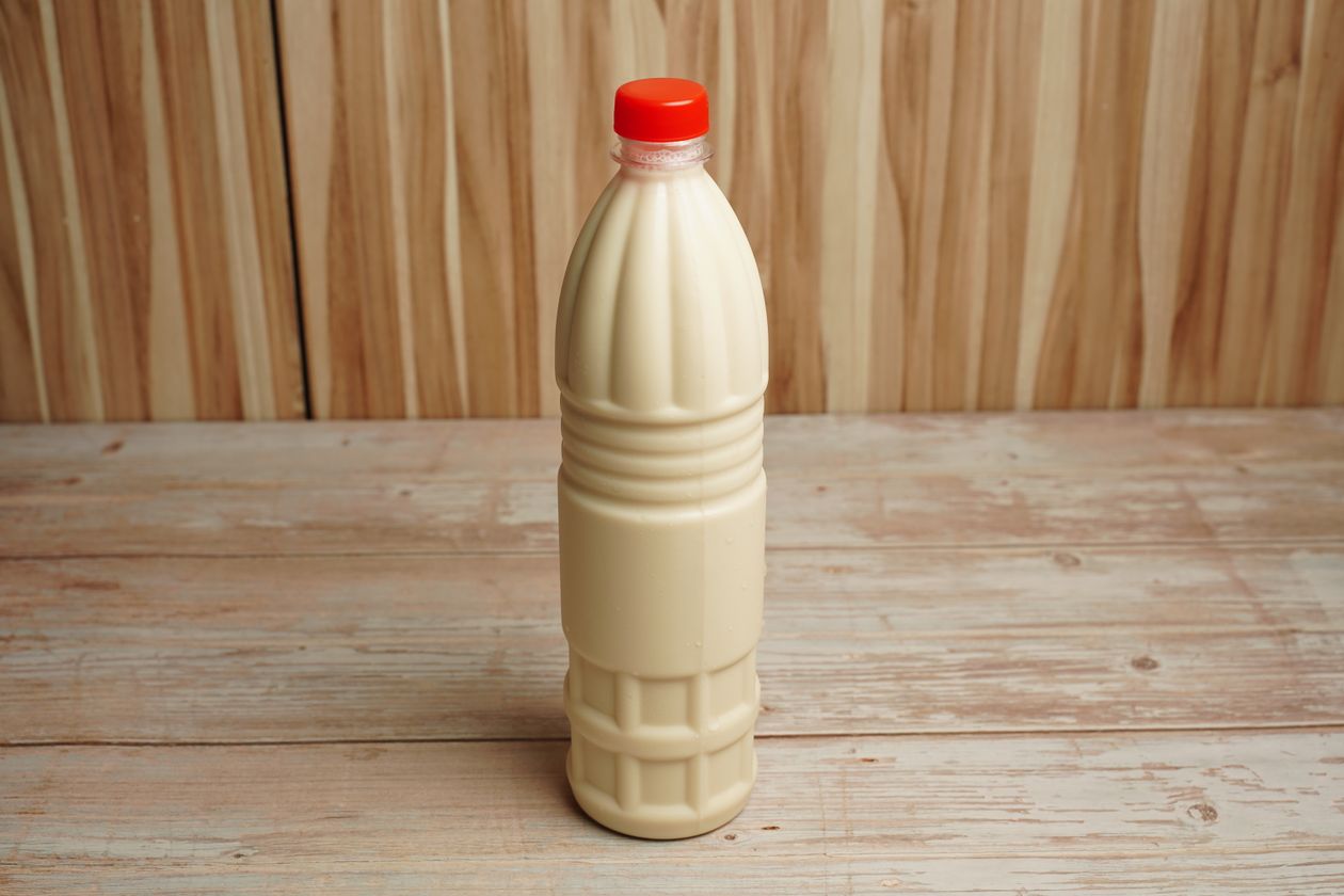 Garrafa de leite sobre mesa de madeira, contexto de doce de leite sem lactose