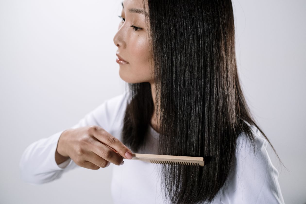 Mulher penteando o cabelo com escova, contexto de melhor escova de cabelo infantil
