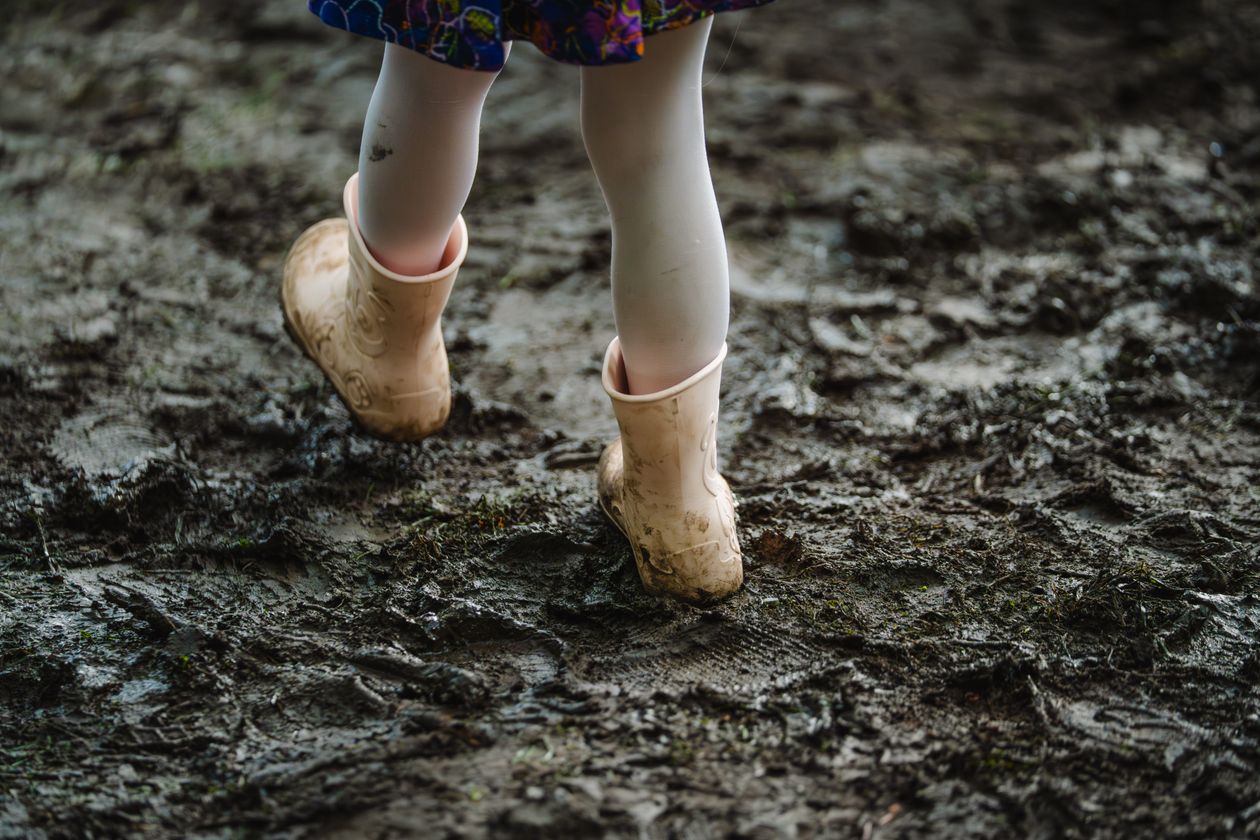 Criança usando galocha infantil para brincar em poça de água na chuva