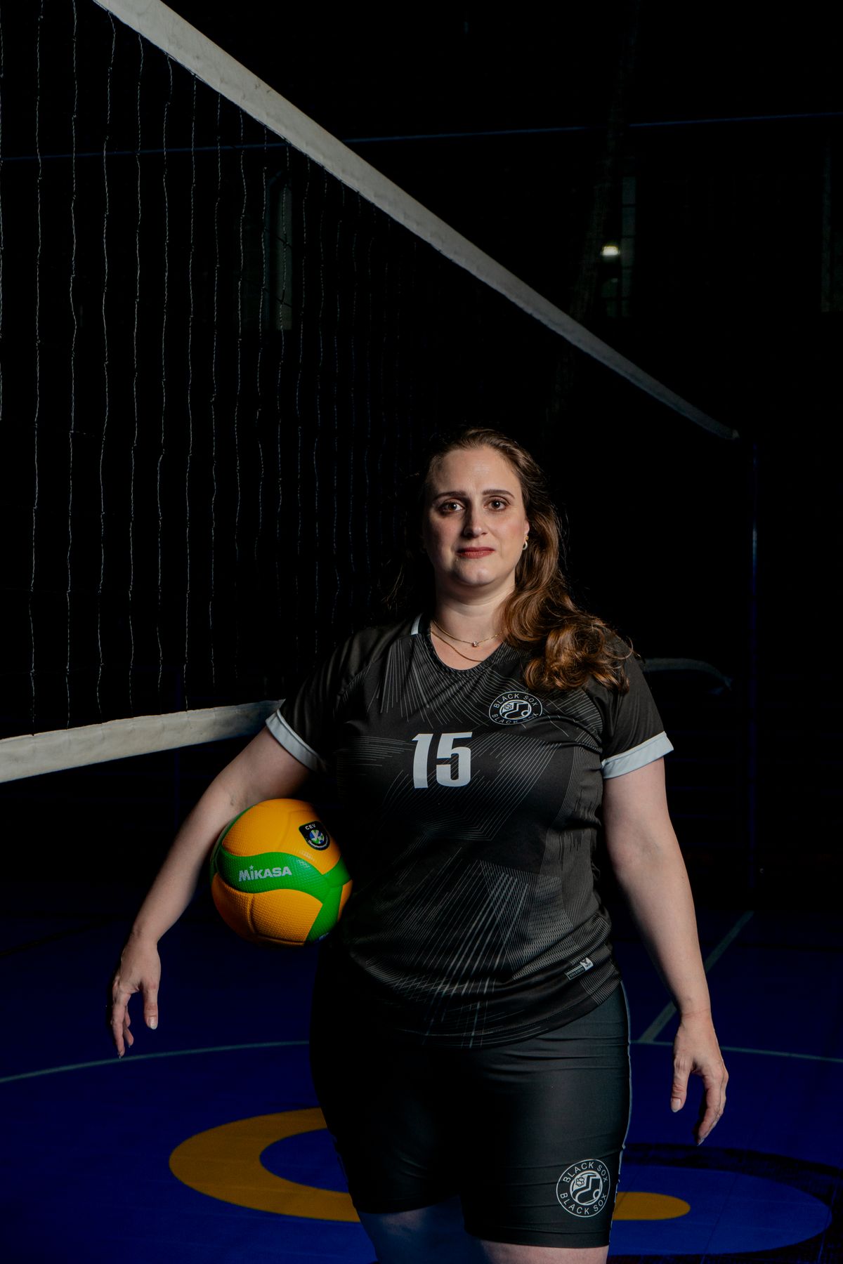 Jogadora de vôlei feminino em quadra segurando a bola, contexto de tênis de vôlei e partida