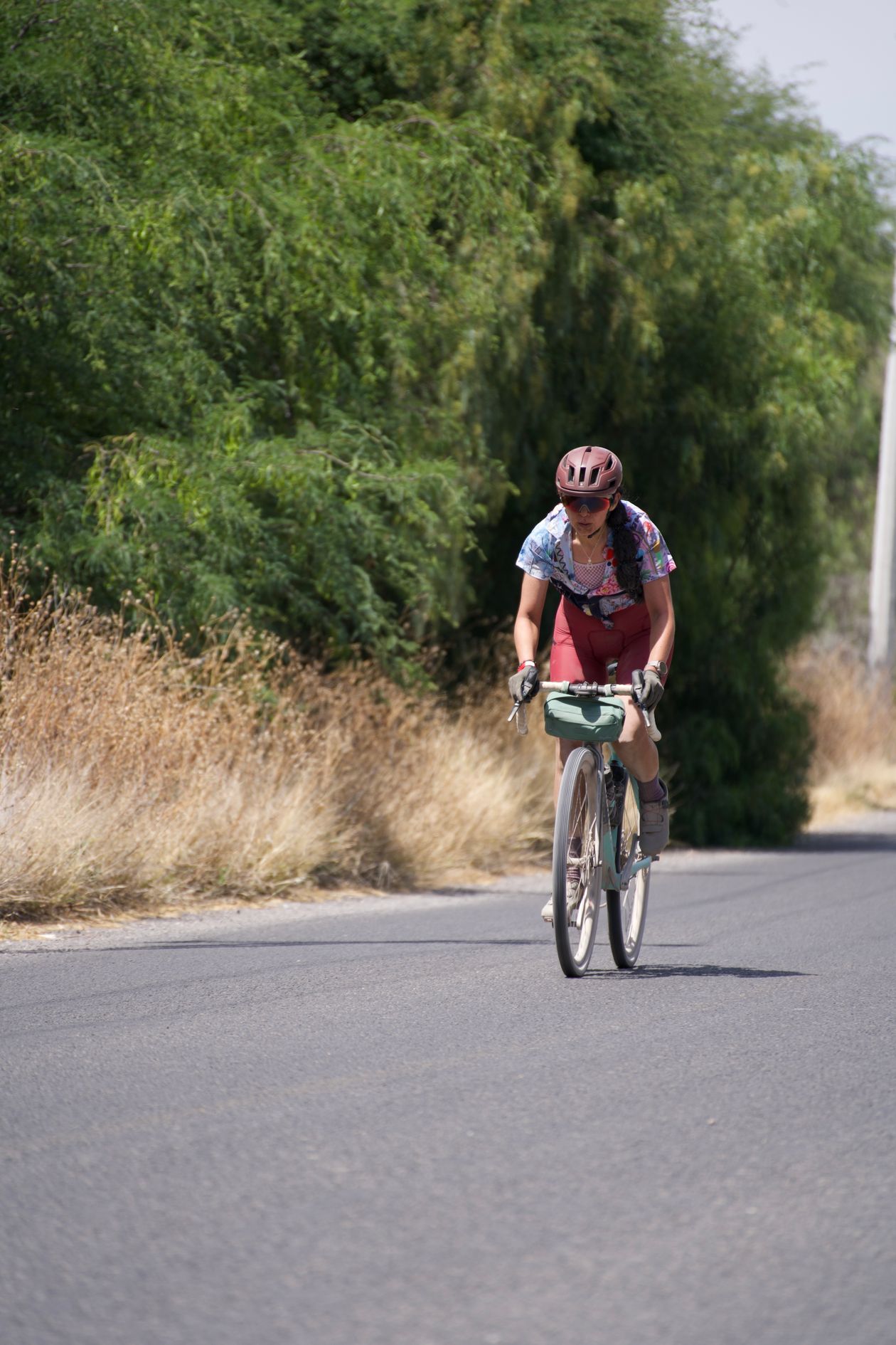Mulher pedalando bicicleta em estrada, contexto de macaquinho de ciclismo feminino