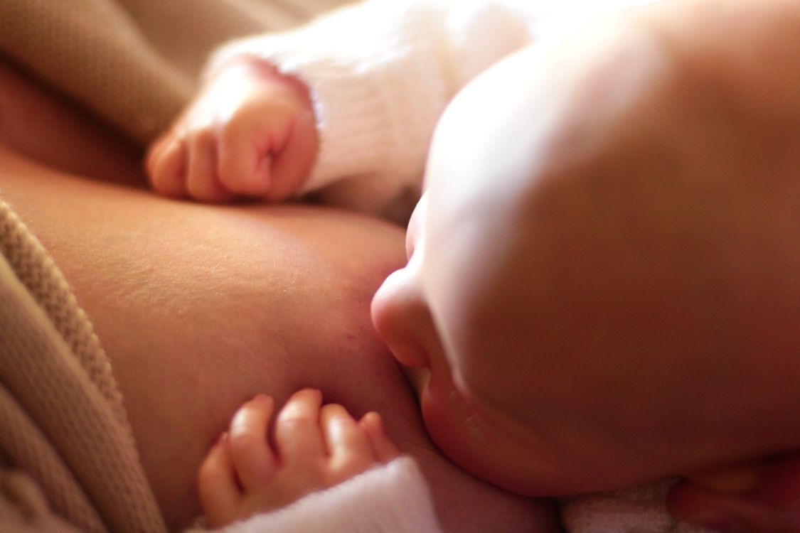 Mãe amamentando o bebê em ambiente natural, contexto de ordenha e leite materno