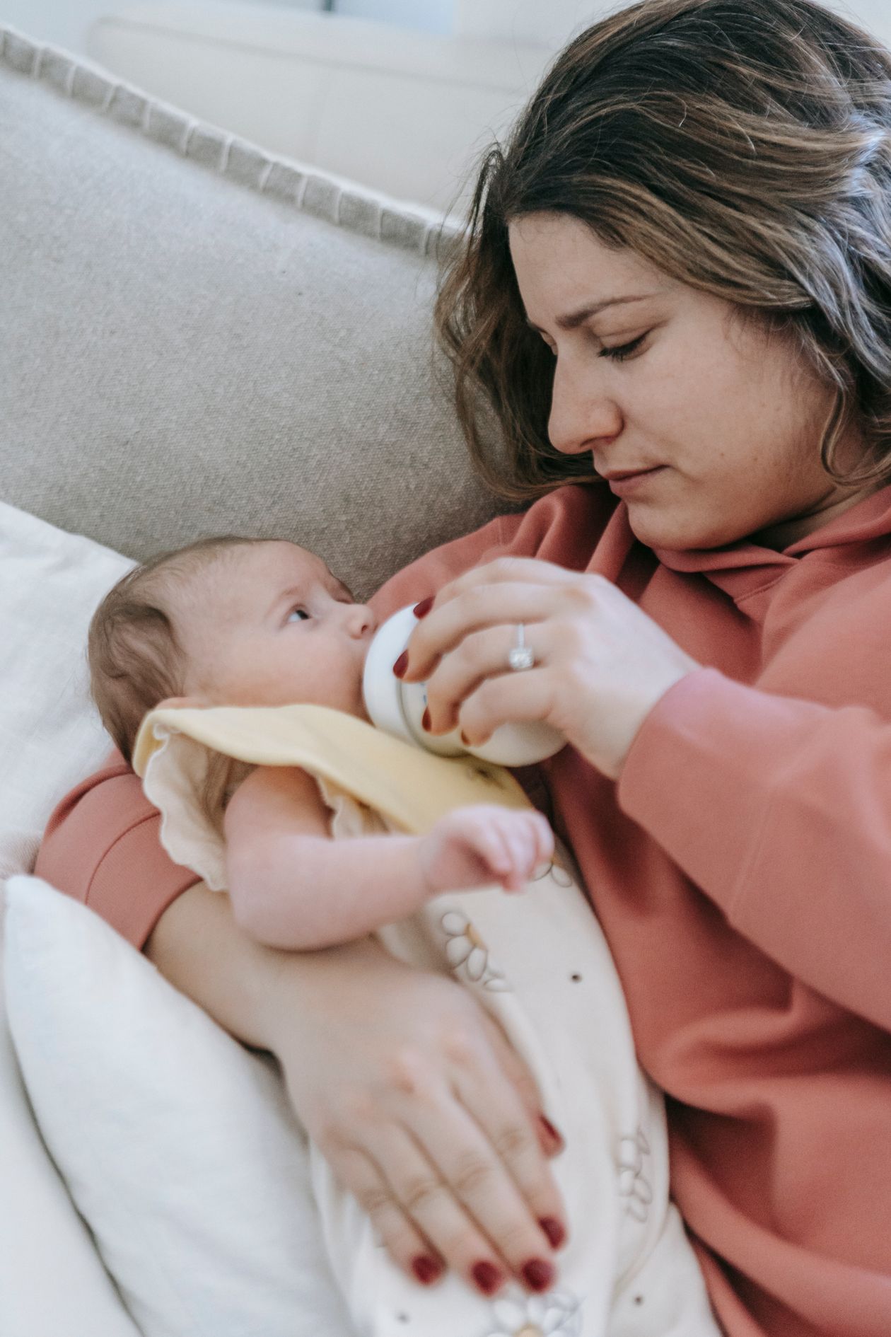Mãe dando mamadeira para o bebê no colo, contexto de melhor mamadeira para bebê