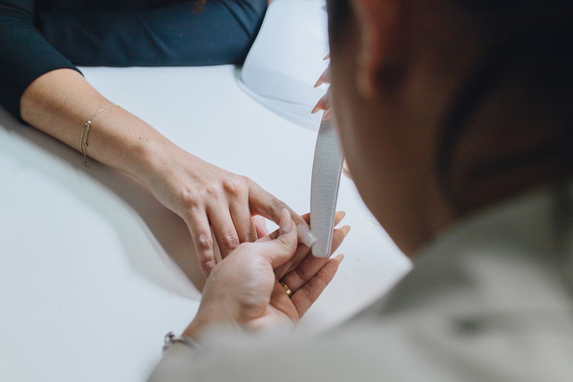 Manicure realizando cutilagem com alicate, contexto de precisão e cuidado com as unhas