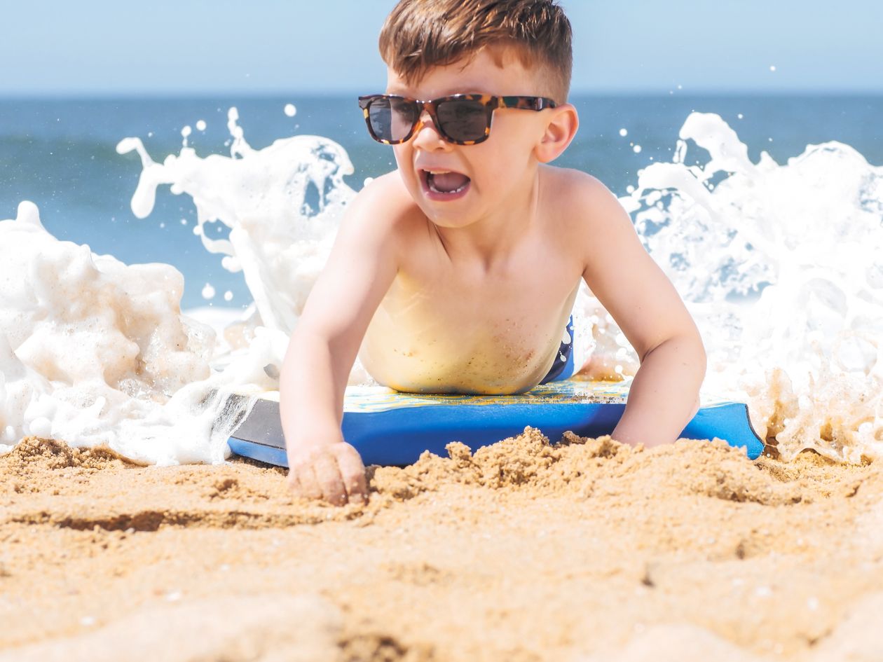 Criança de óculos de sol na praia, contexto de óculos de sol infantil