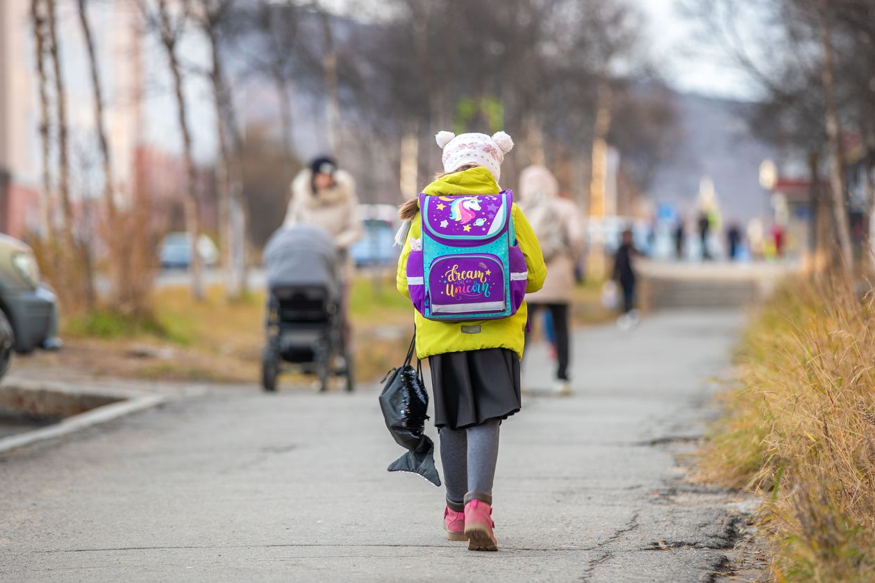 Criança a caminho da escola com mochila colorida