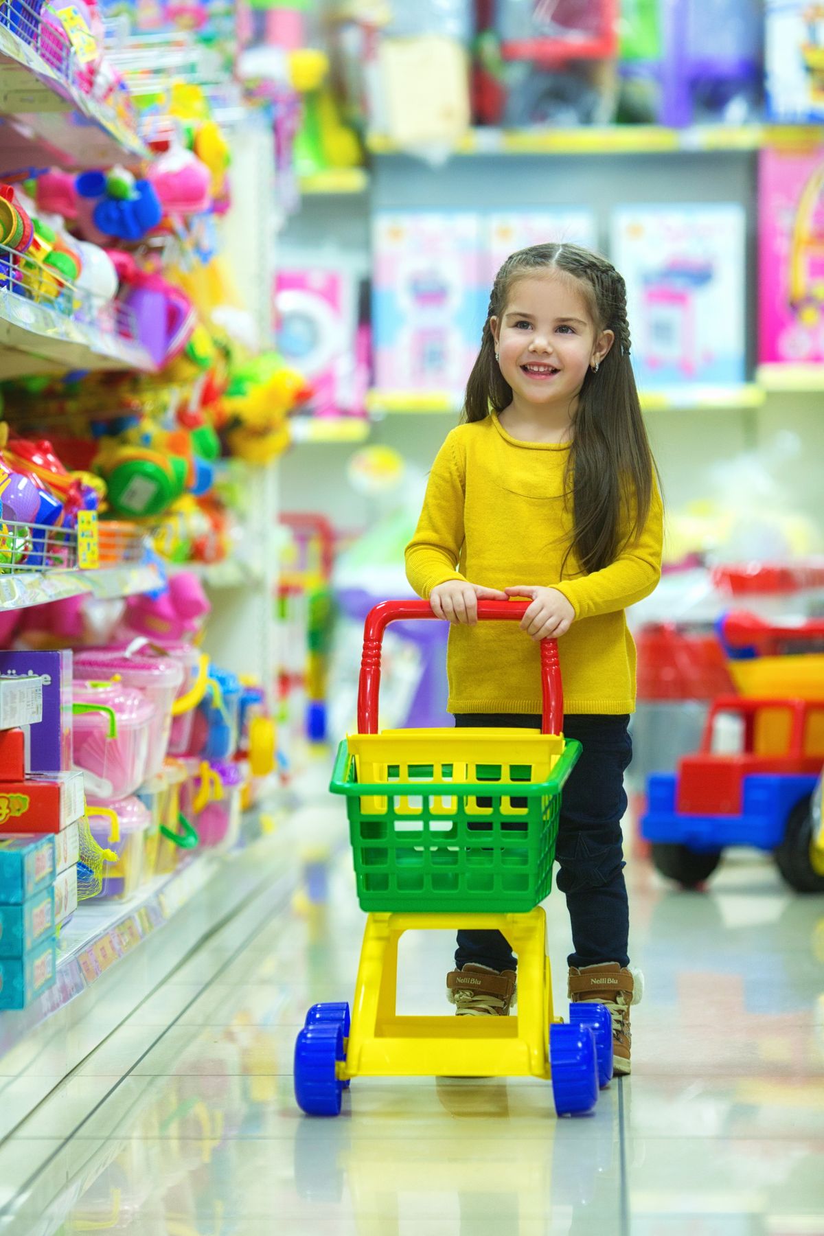 Menina empurrando carrinho de brinquedo em corredor, momento do faz de conta de supermercado infantil