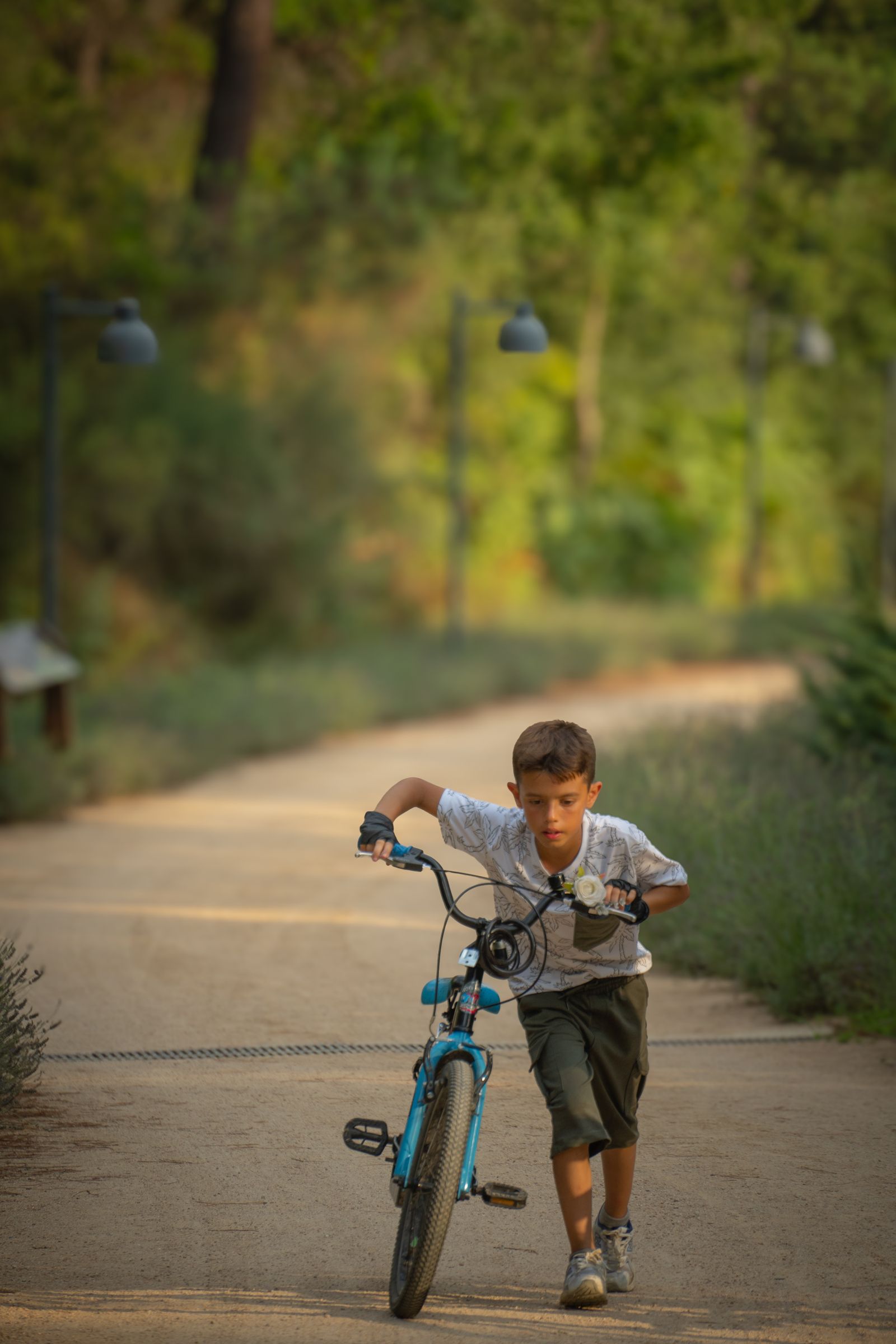 Menino guiando bicicleta aro 16 em parque ensolarado - contexto de uso da bicicleta infantil