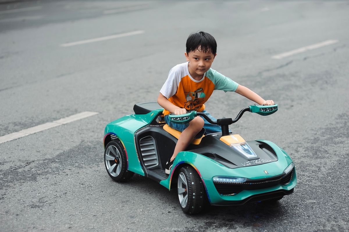 Menino em carrinho elétrico na rua, contexto de uso do carrinho elétrico infantil ao ar livre