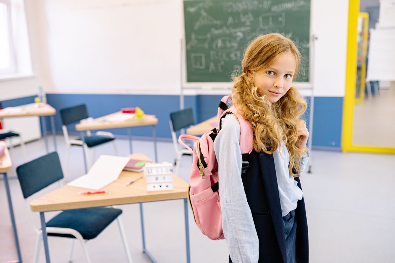 Menina com mochila nas costas, contexto de mochila de rodinha infantil