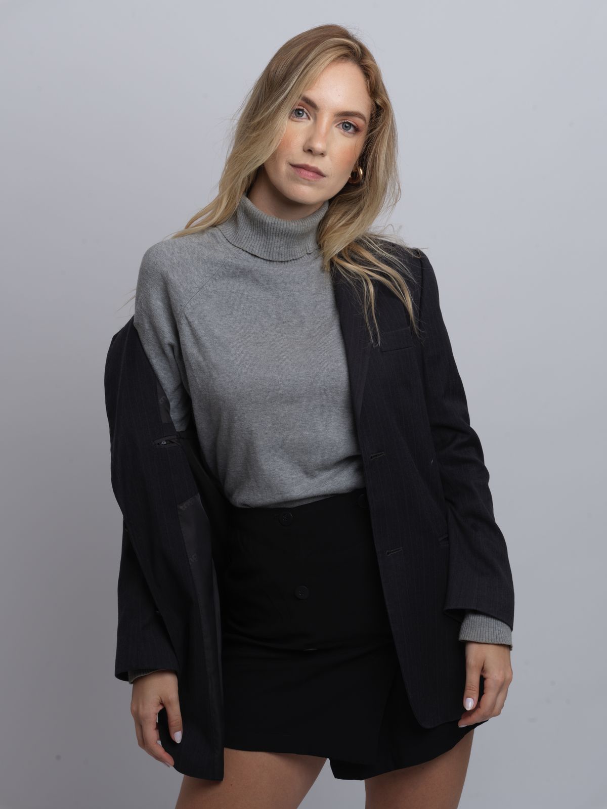 Mulher profissional de blazer preto posando confiante, contexto de tecido para blazer feminino e alfaiataria