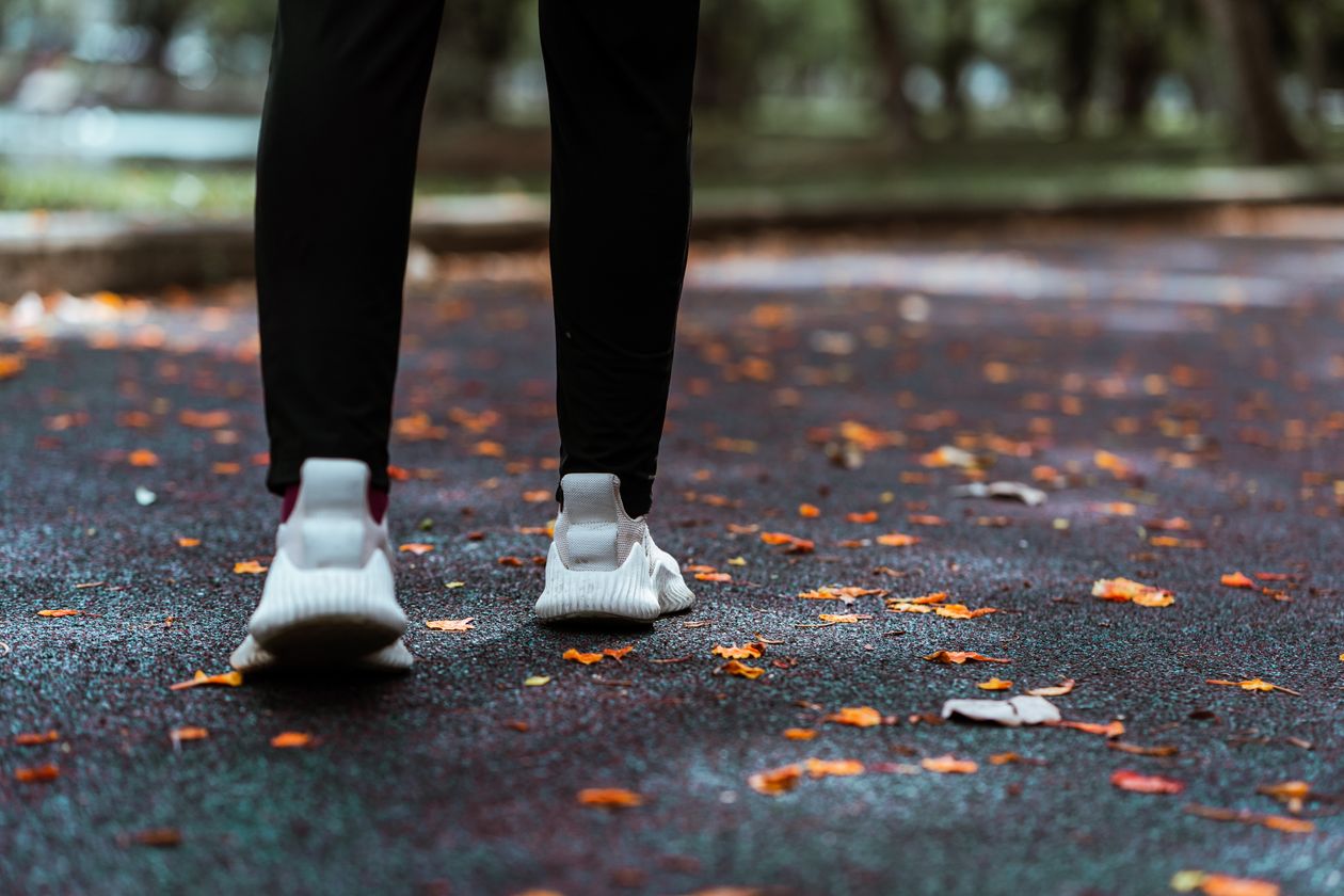 Mulher caminhando em calçada de parque com tênis Mizuno feminino, contexto de tênis mizuno para caminhada feminino