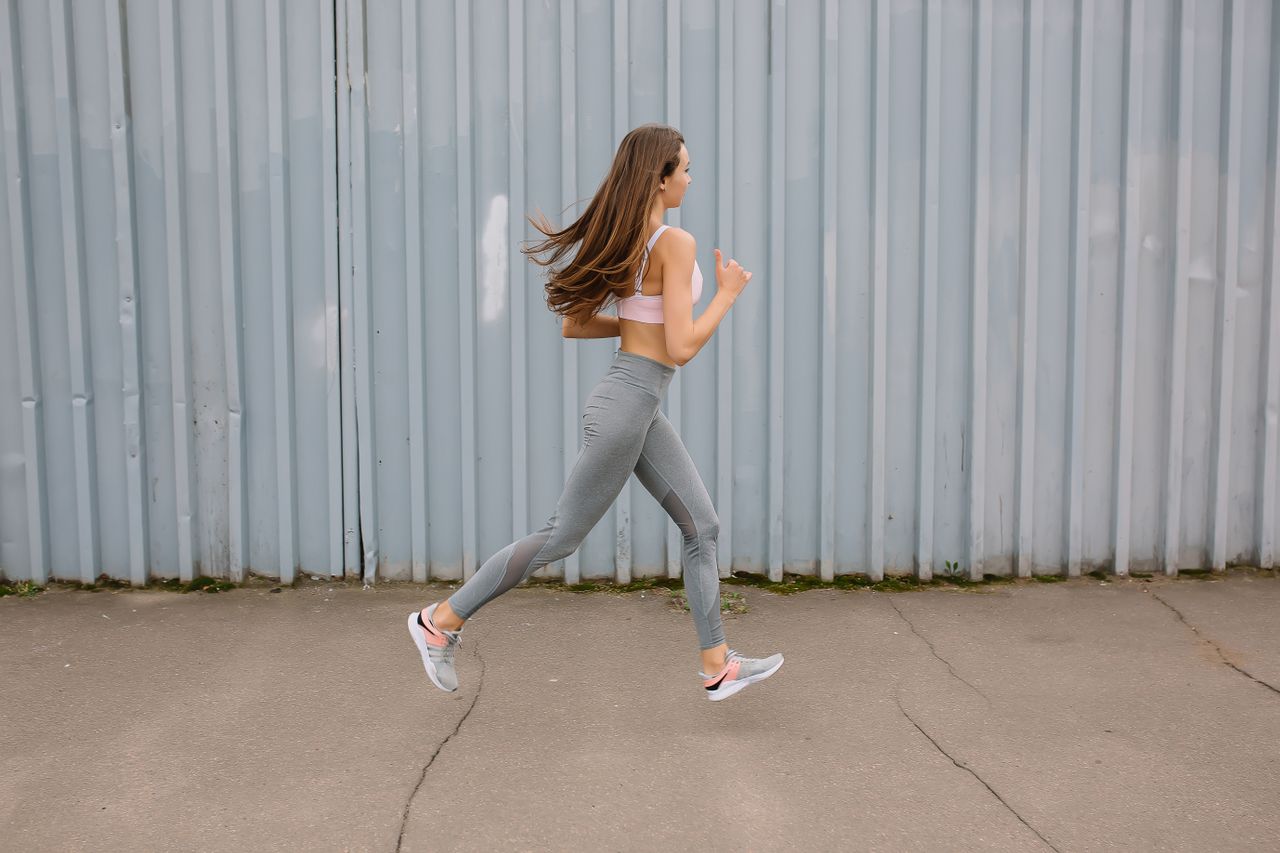 Mulher caminhando em rua urbana com roupa esportiva, contexto de caminhada diária e estilo de vida ativo