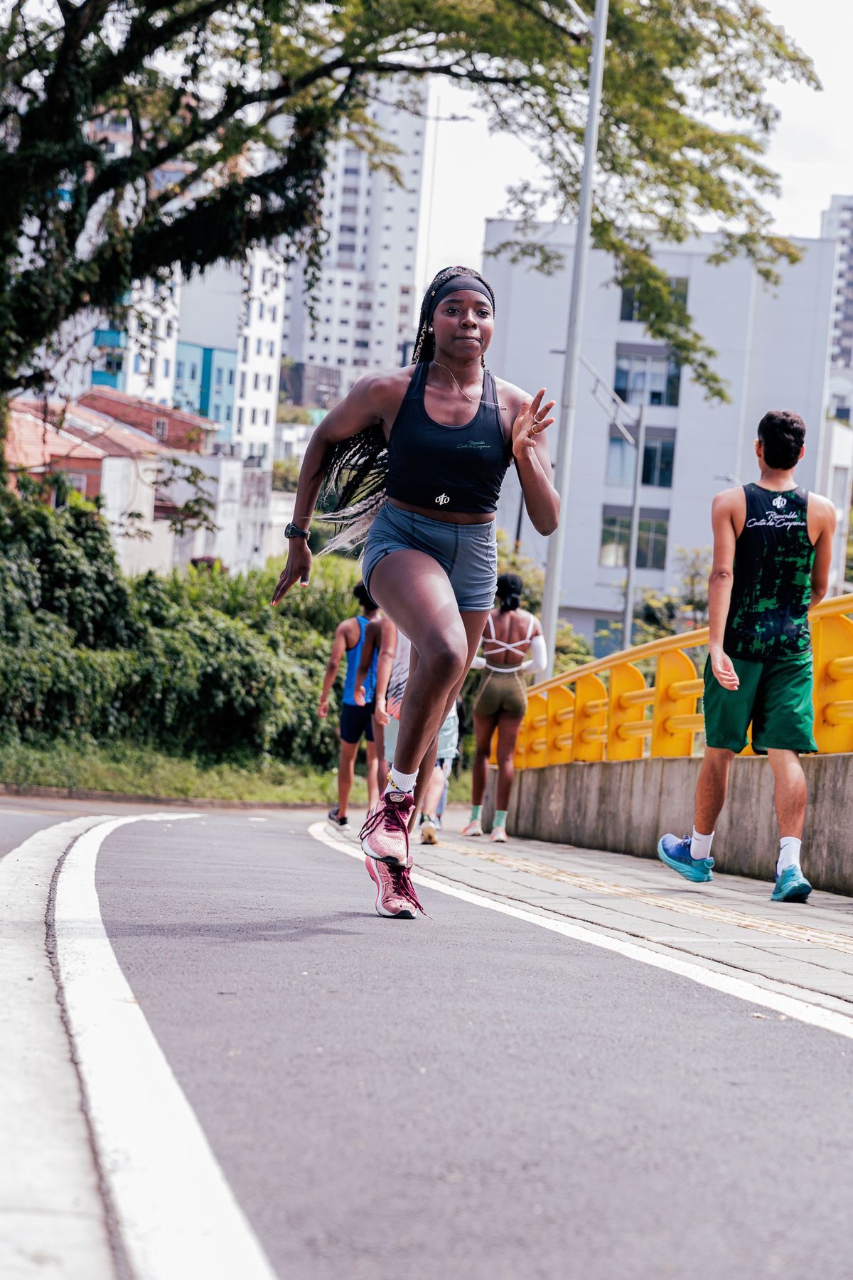 Atleta feminina correndo em pista urbana ao ar livre, contexto de treino de corrida e roupa esportiva