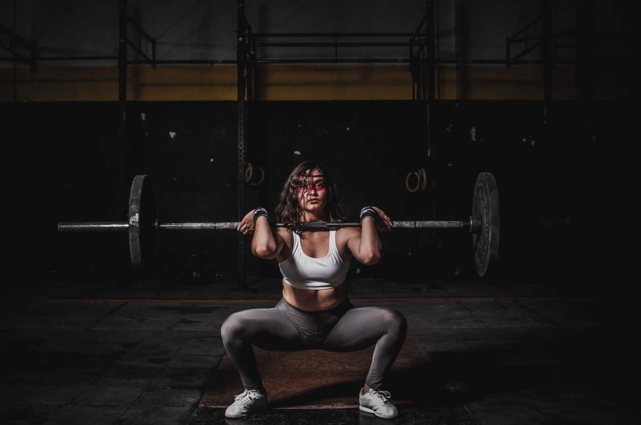 Mulher praticando crossfit com barra em box de treino, contexto de tênis feminino para crossfit