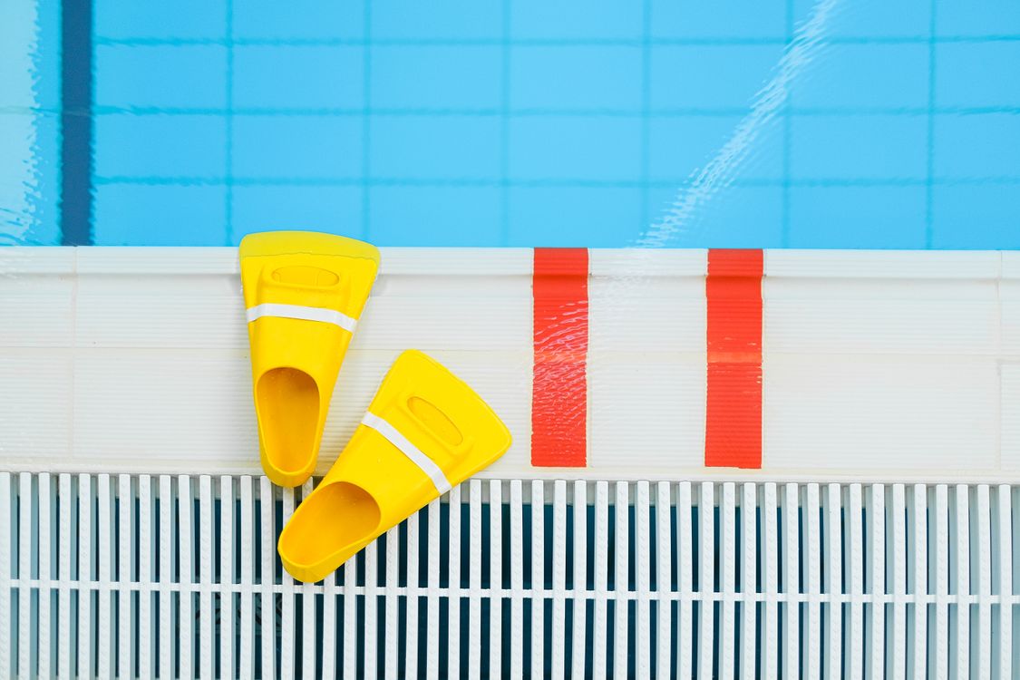Mulher com touca de natação na piscina, contexto de proteção capilar durante o treino