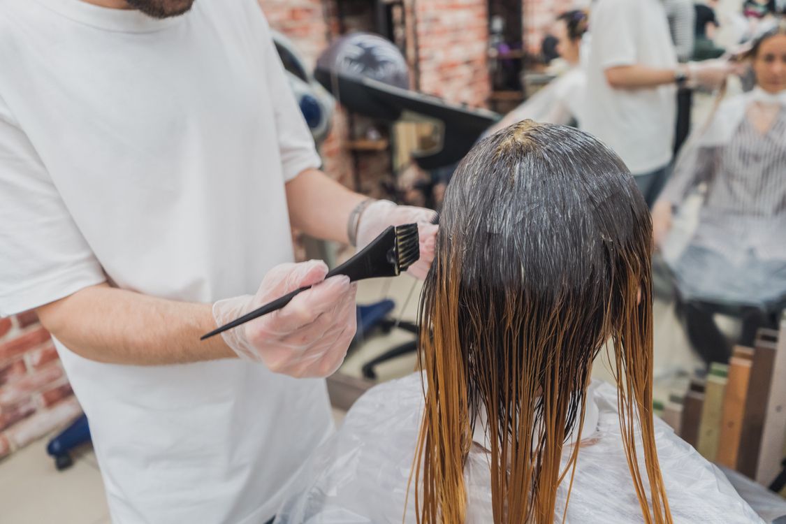 Mulher secando os cabelos em salão, contexto de cuidado capilar com secador doméstico