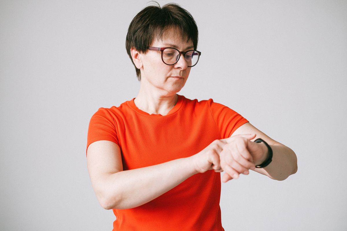 Mulher verificando smartwatch no pulso em ambiente interno, contexto de relógio inteligente e saúde