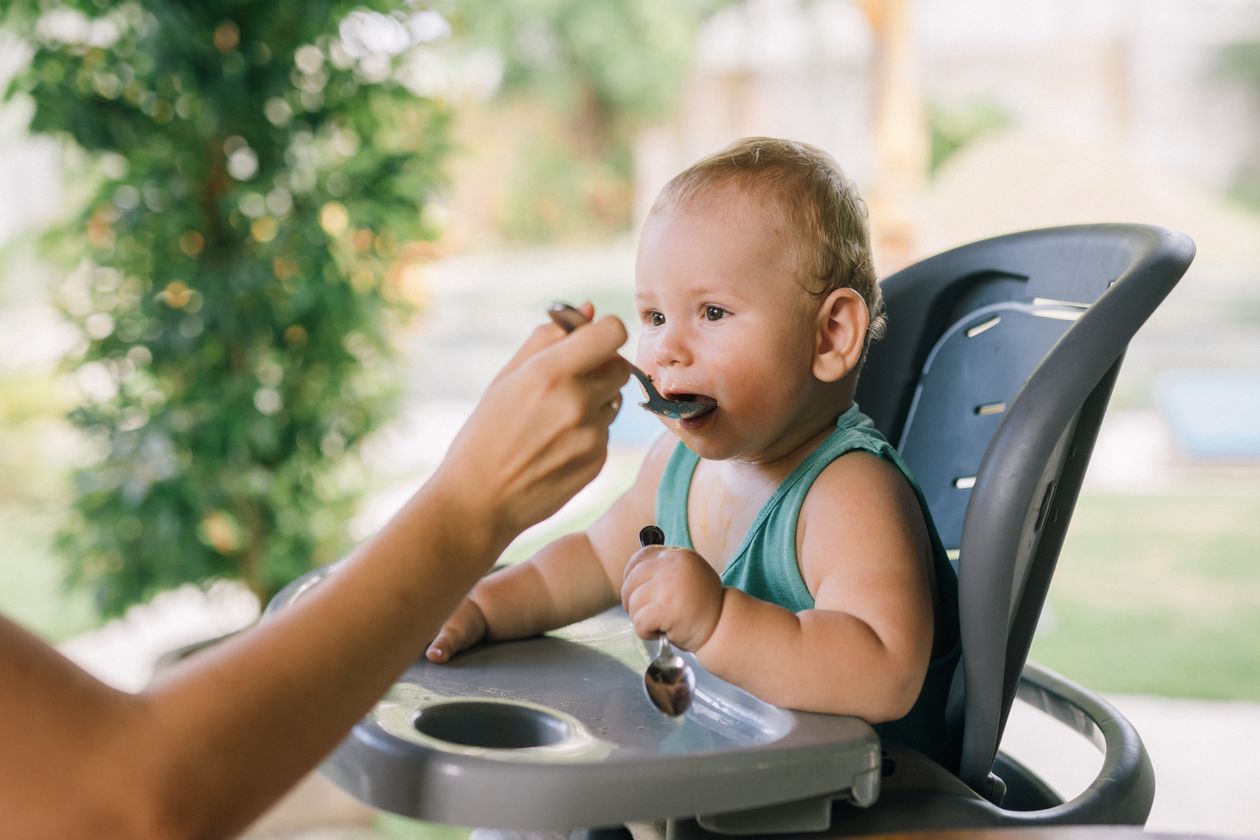 Bebê comendo papinha na cadeirinha