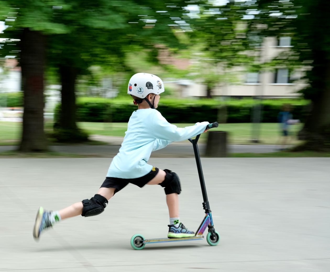 Criança andando de patinete com capacete