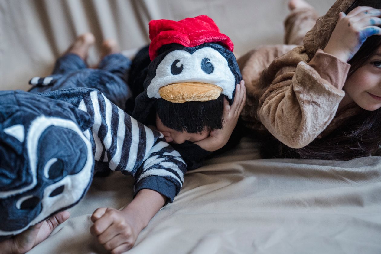 Crianças de pijama brincando na cama, contexto de melhor pijama infantil